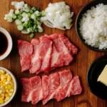 Key ingredients for a pepper lunch recipe, including thinly sliced beef, short-grain rice, corn kernels, chopped onions, soy sauce, and butter, neatly arranged on a wooden kitchen counter